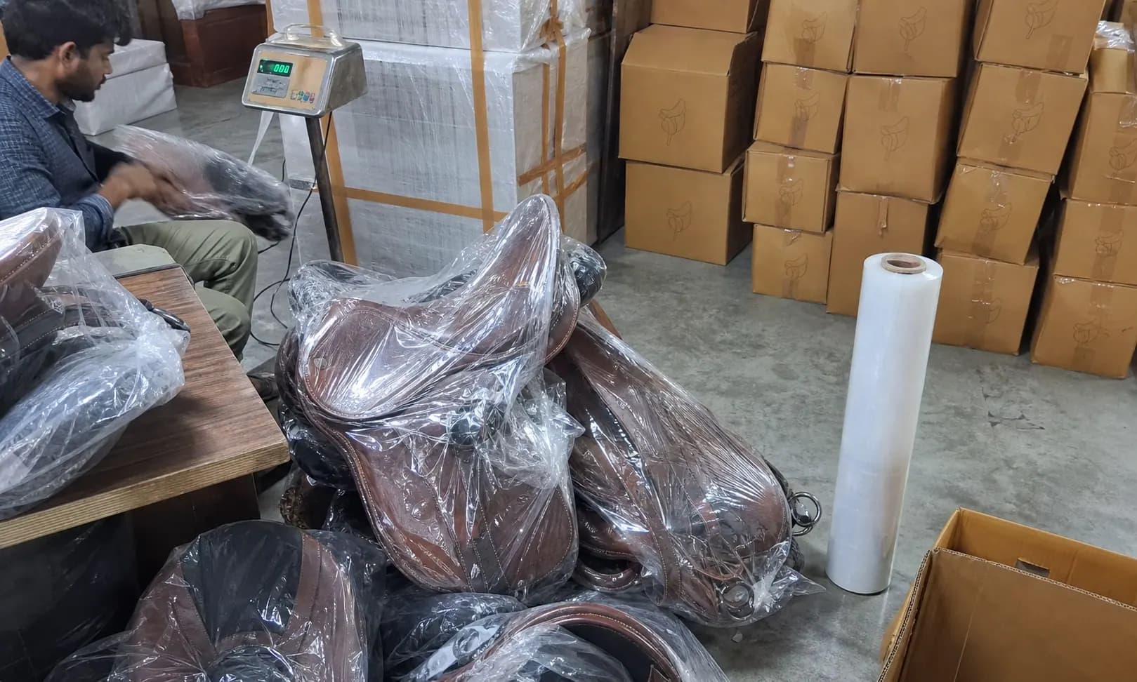 Raw mobile photo of export packing area in Indian saddlery factory