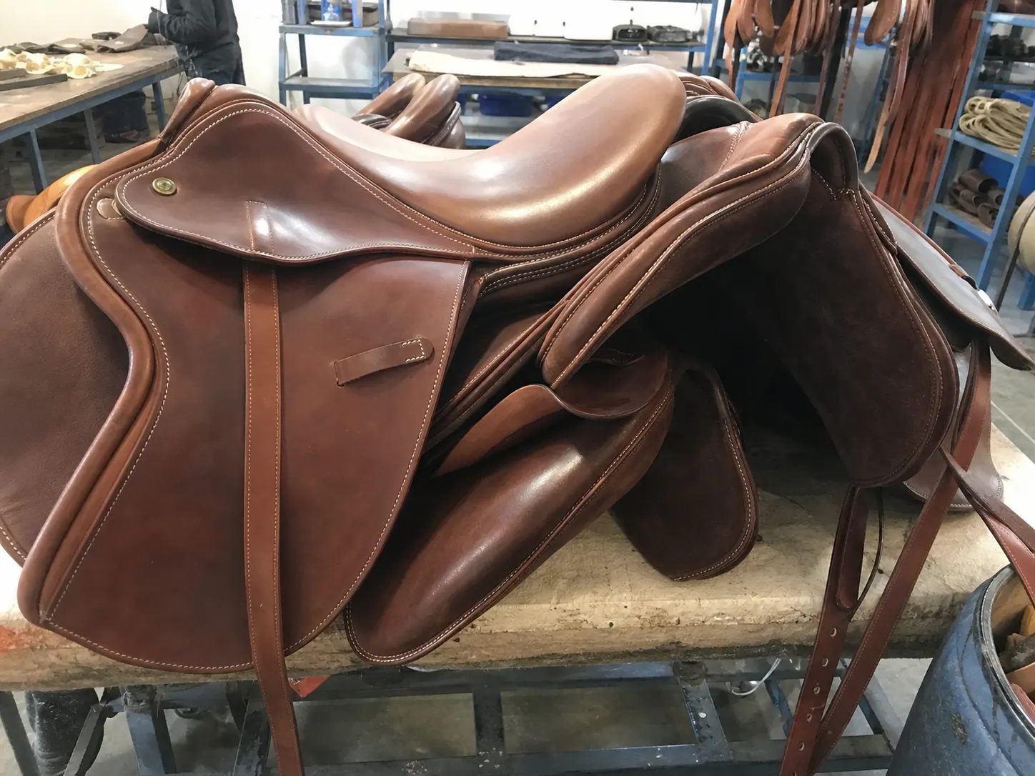 Raw mobile photo of leather saddles on inspection table