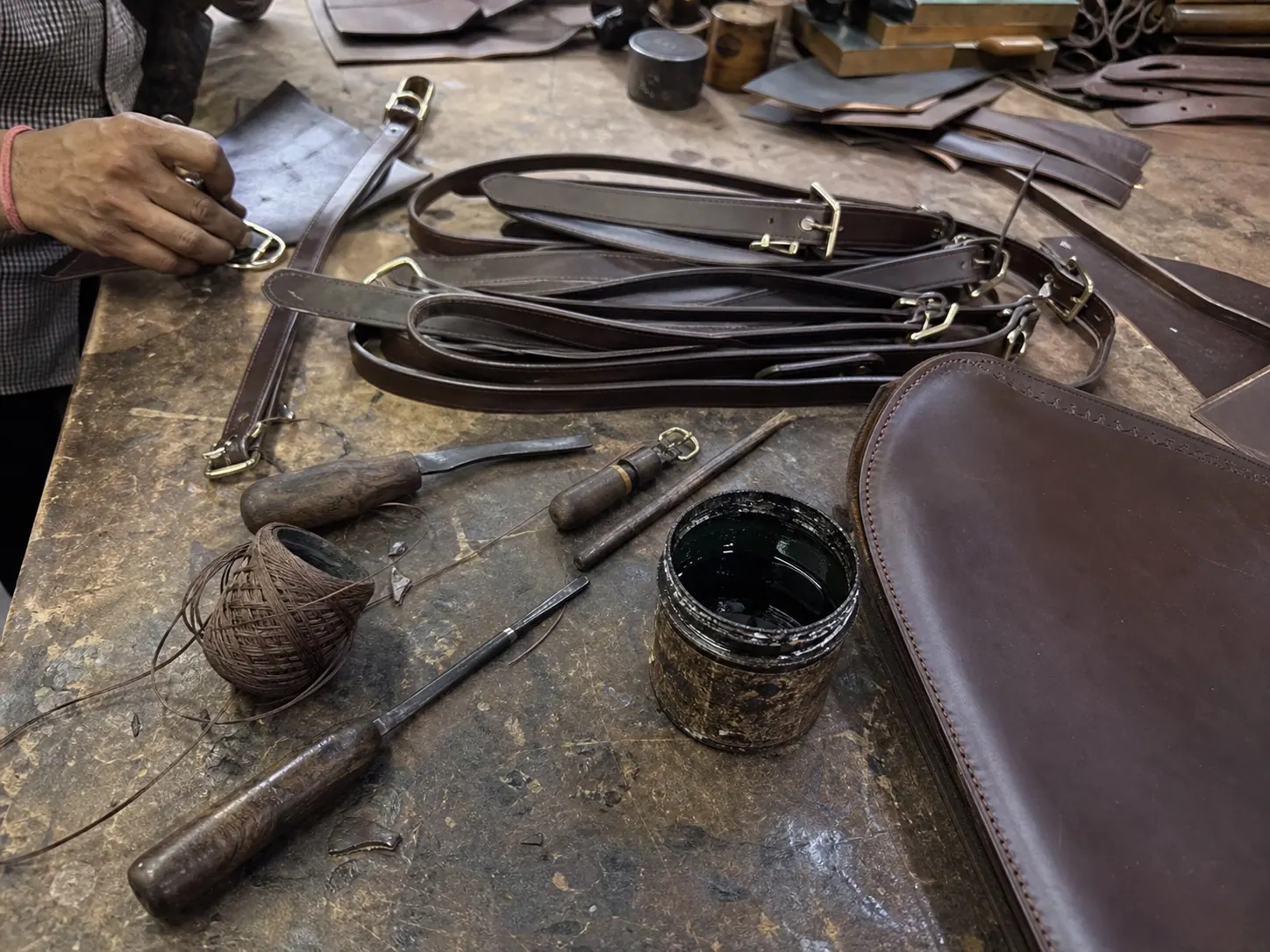 Raw mobile photo of leather working table with tools and straps