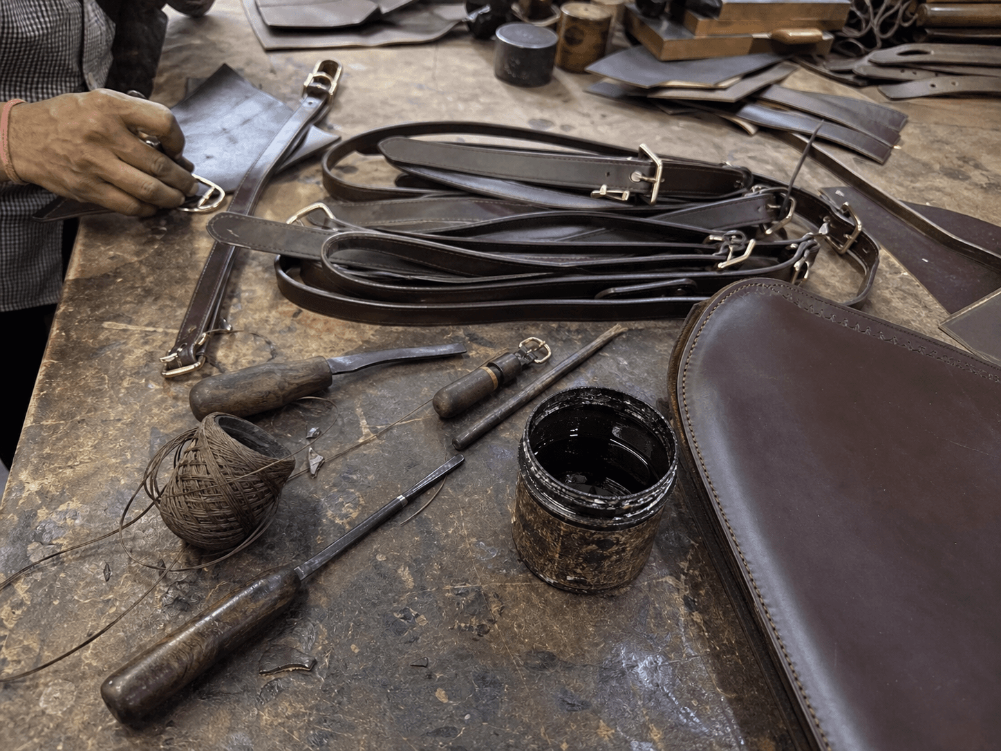 Raw mobile photo of leather working table with tools and straps
